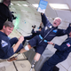John Kemp floating with four prosthetic limbs outreached. He’s holding his new book, Disability Friendly: How to Move from Clueless to Inclusive.